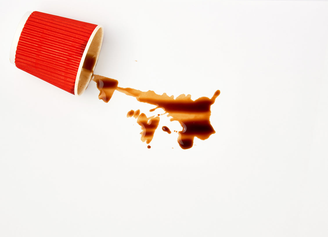 Red paper coffee cup spilling coffee on paper