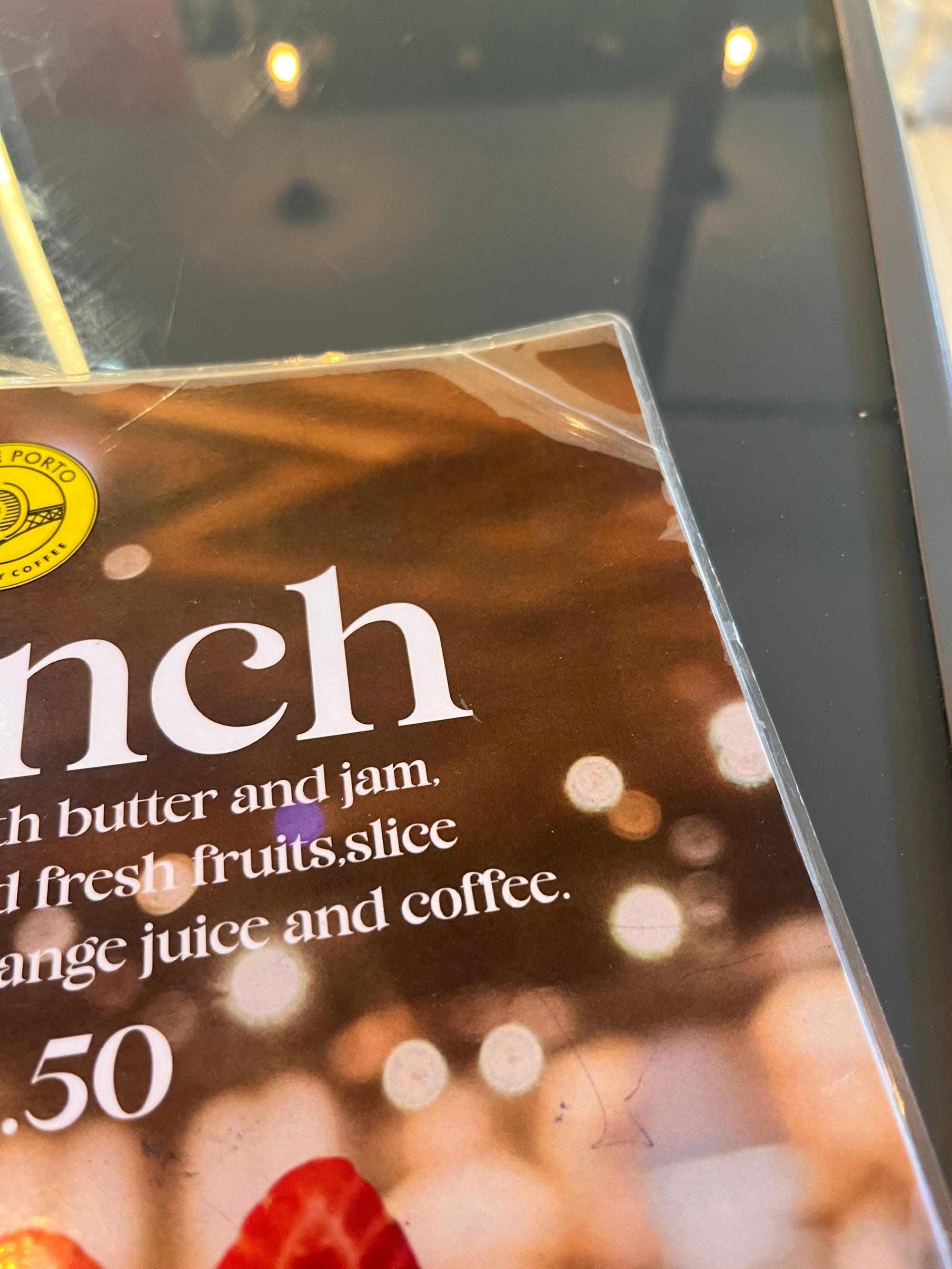 Close-up of an encapsulated menu corner showing the clear border lifting and the surface scratched and cracked from regular use.