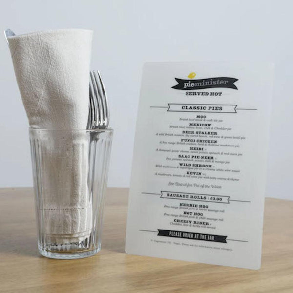 A5 portrait Pie menu on a table beside a glass filled with napkin and cutlery to show scale
